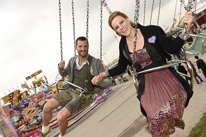 Martin Tomszyk mit Ehefrau Christina Surer fahren Kettenkarussell. Das Dirndl hält!