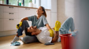 Young happy couple relaxing on the floor after cleaning their house together.