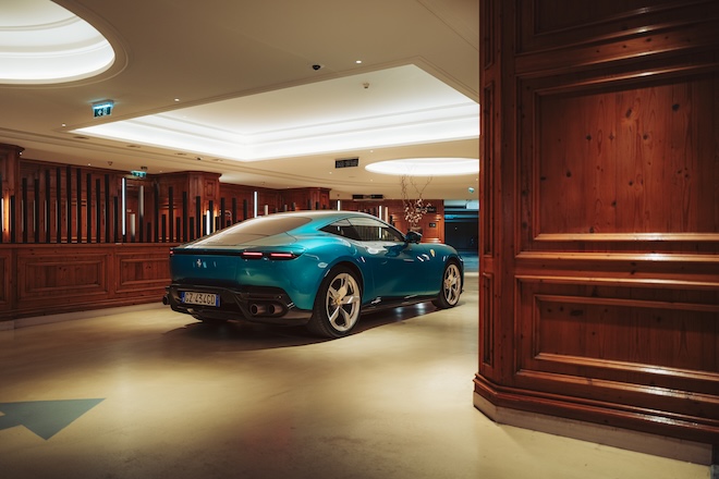 Souveräne Präsenz im exklusiven Licht: Die Heckansicht des 640 PS starken Grand Tourers bringt die geschwungenen Kurven und das emotionale Design des Roma-Nachfolgers in der edlen Kulisse des Interalpen-Hotels perfekt zur Geltung.
