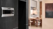 40 Jahre Gaggenaus großer Backofen: Warum der EB 333 bis heute fasziniert Gaggenau Backofen EB 333 in einer dunklen Schrankwand neben einer hellen Küche mit Esstisch.