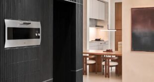 Gaggenau Backofen EB 333 in einer dunklen Schrankwand neben einer hellen Küche mit Esstisch.