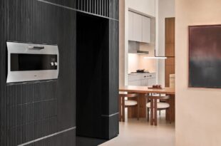 Gaggenau Backofen EB 333 in einer dunklen Schrankwand neben einer hellen Küche mit Esstisch.