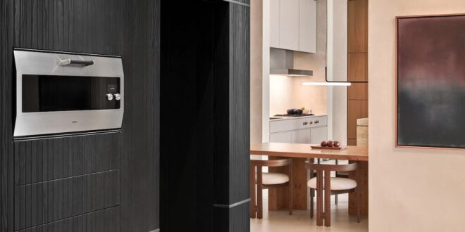 Gaggenau Backofen EB 333 in einer dunklen Schrankwand neben einer hellen Küche mit Esstisch.