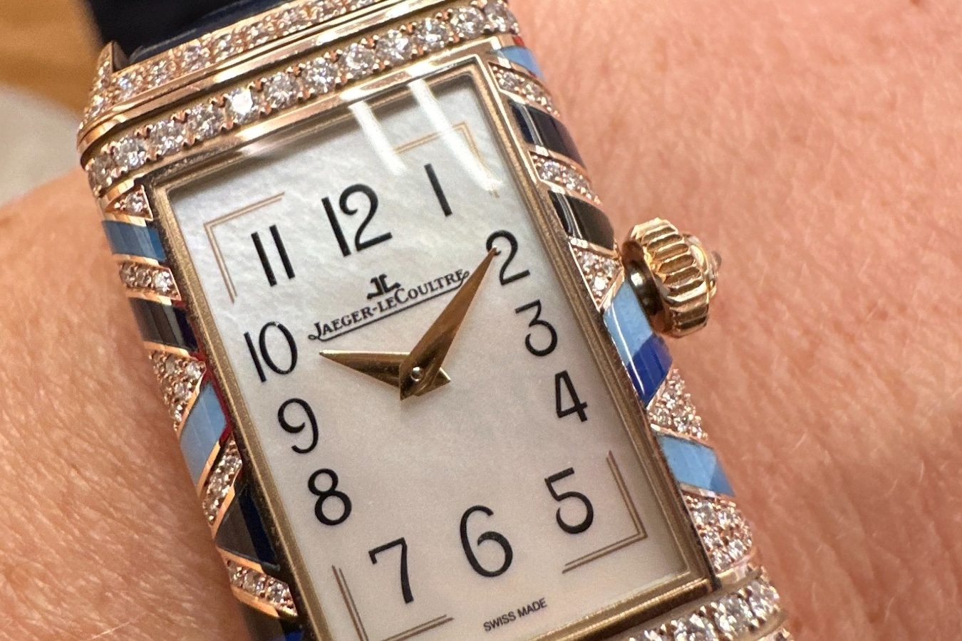 Nahaufnahme einer Jaeger-LeCoultre Reverso am Handgelenk mit hellem Zifferblatt, goldfarbenen Zeigern und steinbesetztem Gehäuse.