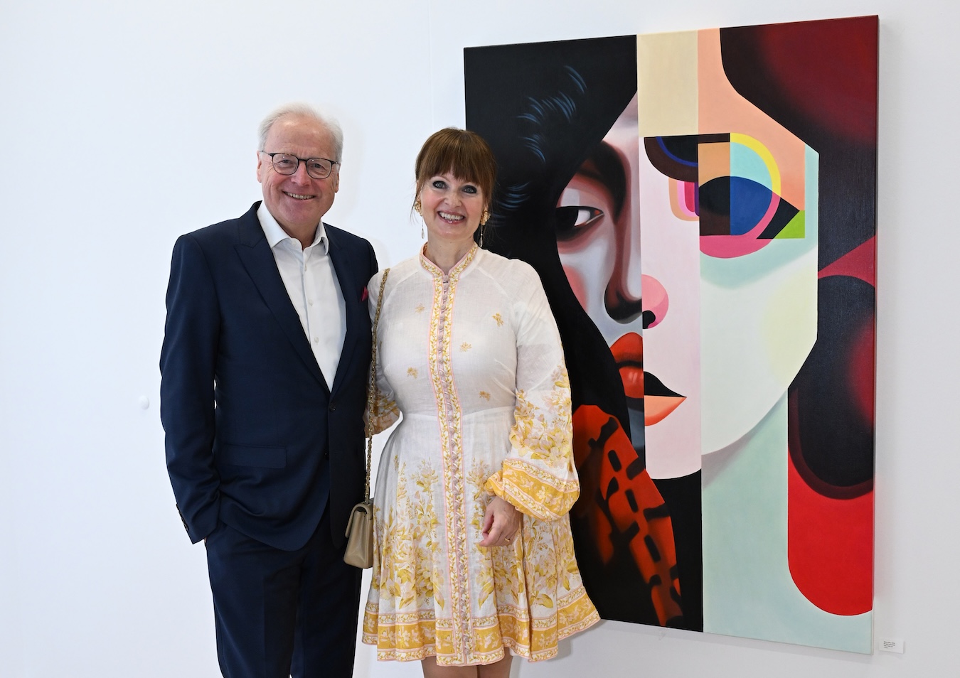 Fritz Esterer und Dr. Sonja Lechner stehen vor einem farbenfrohen, geometrisch gestalteten Frauenporträt von Tanja Hirschfeld bei WTS.